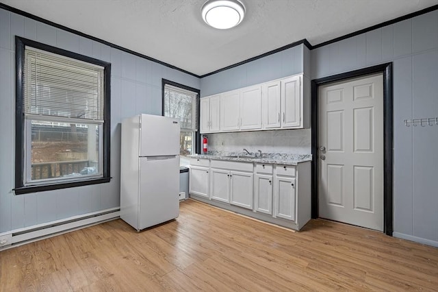 kitchen with freestanding refrigerator, ornamental molding, a baseboard radiator, light wood-style flooring, and white cabinets