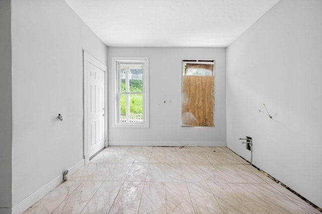 spare room featuring light marble finish flooring and baseboards