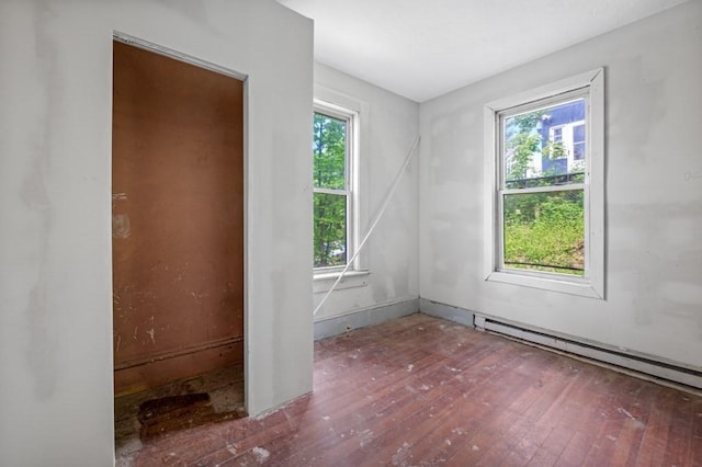 spare room with hardwood / wood-style floors, healthy amount of natural light, and a baseboard radiator