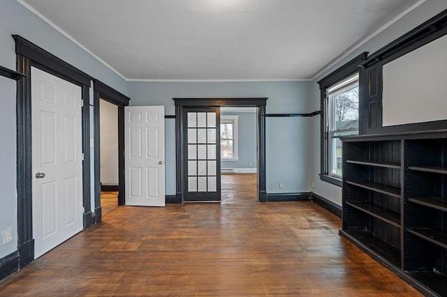 unfurnished bedroom with wood finished floors, ornamental molding, baseboards, and a baseboard heating unit