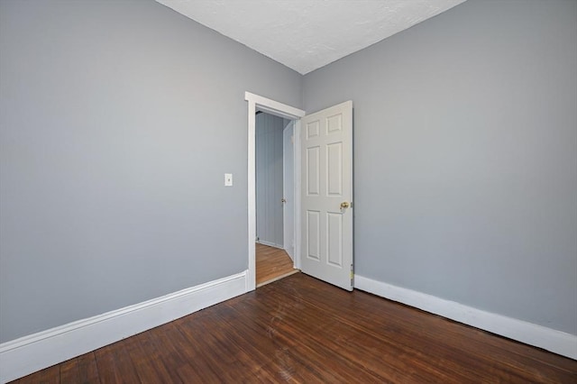 spare room featuring baseboards and wood finished floors