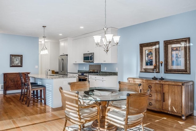 dining space with a notable chandelier, recessed lighting, and light wood-style floors