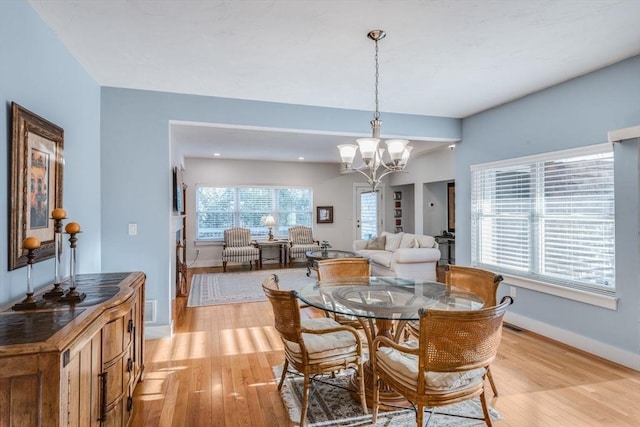 dining space with an inviting chandelier, light wood-style flooring, visible vents, and baseboards