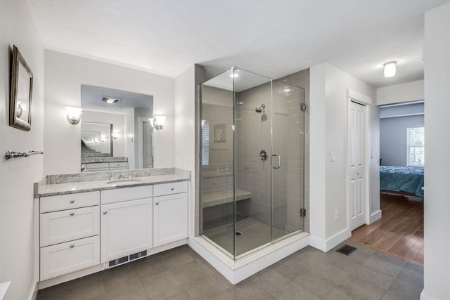 bathroom featuring visible vents, a shower stall, baseboards, and vanity