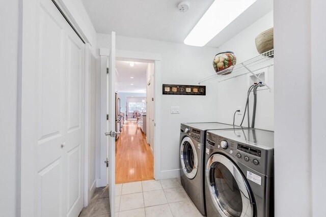 clothes washing area with light tile patterned floors, laundry area, and washing machine and clothes dryer