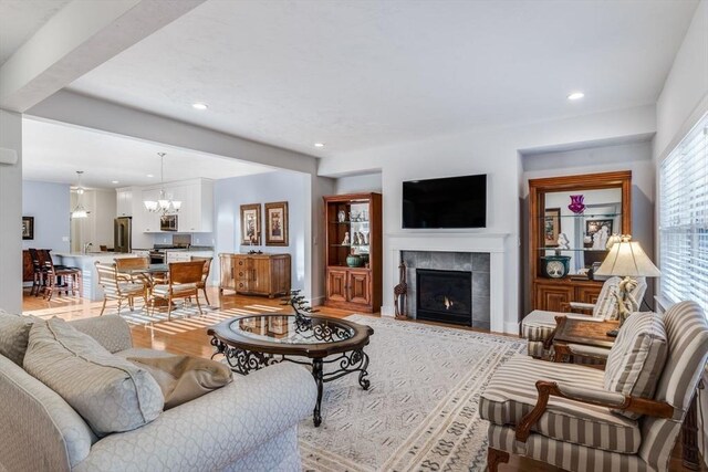 living room with recessed lighting, a notable chandelier, baseboards, light wood-type flooring, and a tiled fireplace