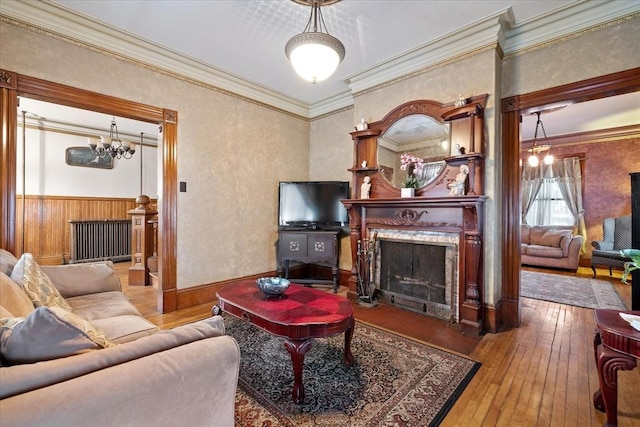 living area featuring a high end fireplace, wood-type flooring, crown molding, and an inviting chandelier