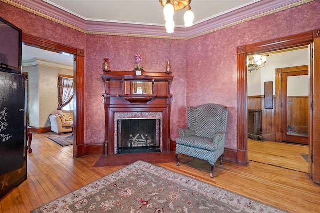 sitting room featuring a notable chandelier, wood-type flooring, a fireplace, and crown molding