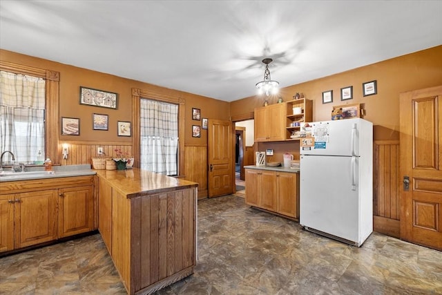 kitchen with a peninsula, a sink, freestanding refrigerator, and a healthy amount of sunlight