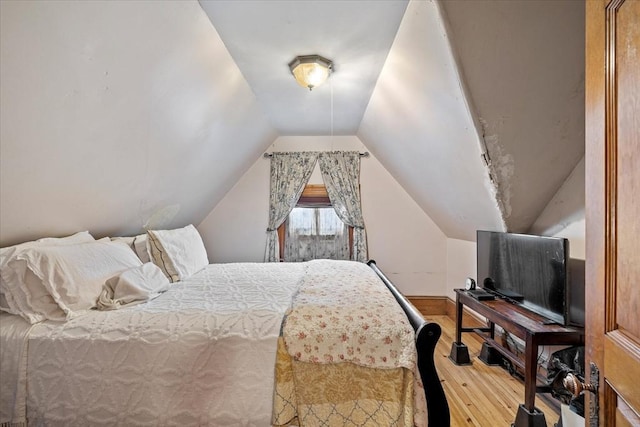 bedroom with vaulted ceiling and wood finished floors