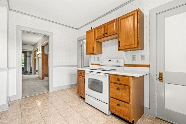 68 Barnard Ave, Watertown, MA 02472 - kitchen featuring white electric range, wallpapered walls, light countertops, brown cabinetry, and a wainscoted wall