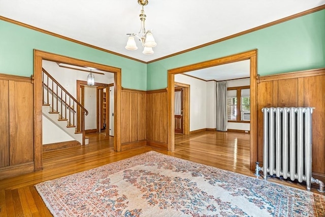 68 Barnard Ave, Watertown, MA 02472 - spare room featuring radiator, a chandelier, wood finished floors, stairs, and crown molding