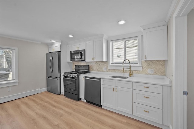 kitchen featuring decorative backsplash, a baseboard heating unit, white cabinets, appliances with stainless steel finishes, and sink