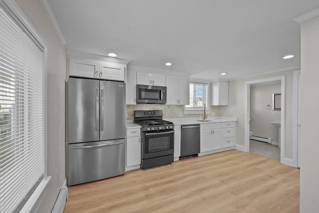 kitchen featuring white cabinetry, appliances with stainless steel finishes, crown molding, sink, and light hardwood / wood-style flooring