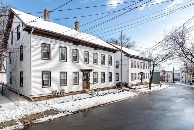 view of front of house featuring entry steps, a chimney, and fence