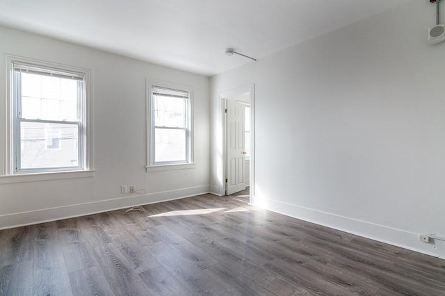 empty room featuring baseboards and dark wood-style flooring