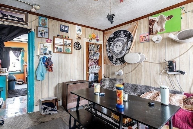 carpeted dining area featuring wooden walls, ornamental molding, and a textured ceiling