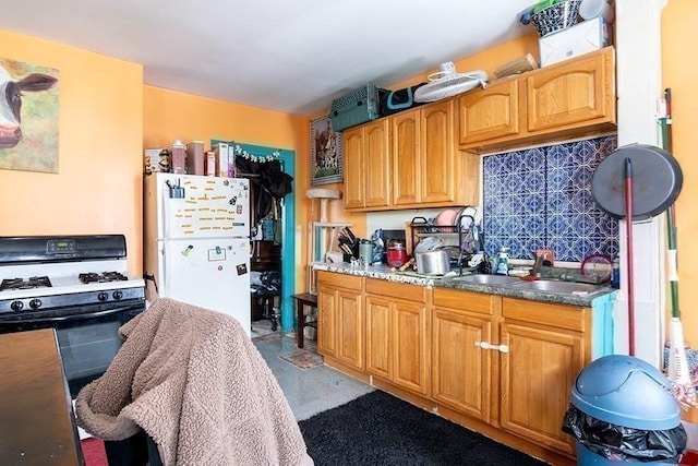 kitchen with a sink, gas range, and freestanding refrigerator