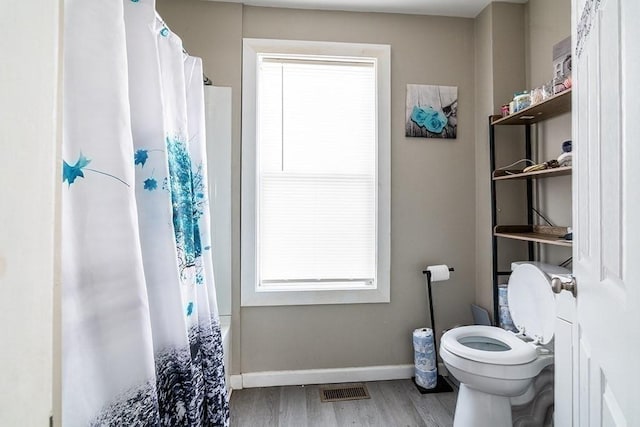 bathroom with visible vents, toilet, curtained shower, wood finished floors, and baseboards