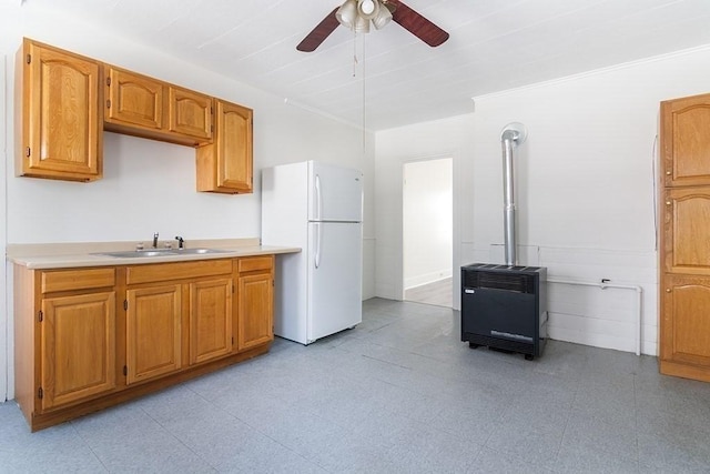 kitchen with heating unit, light floors, freestanding refrigerator, a sink, and light countertops