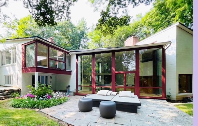 rear view of house featuring an outdoor hangout area, a chimney, a patio, and a sunroom