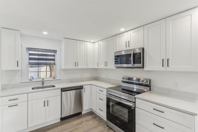 kitchen with white cabinetry, appliances with stainless steel finishes, sink, and light hardwood / wood-style flooring