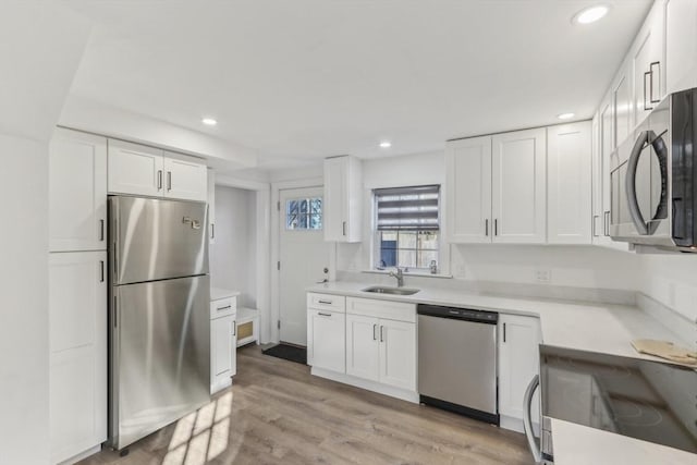 kitchen with white cabinetry, sink, light wood-type flooring, and appliances with stainless steel finishes