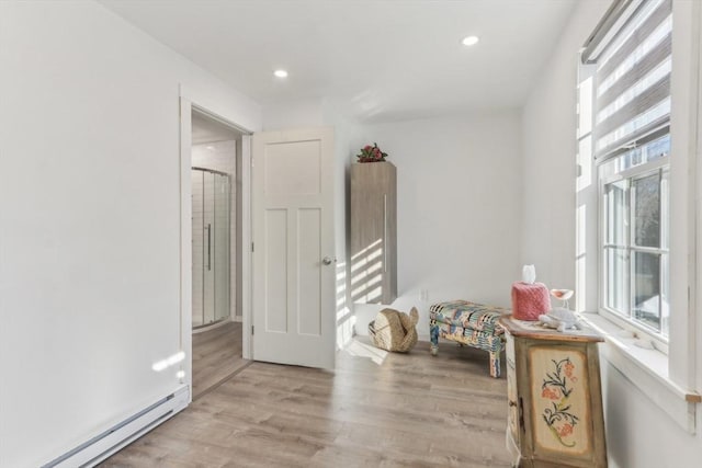 corridor featuring baseboard heating and light hardwood / wood-style flooring