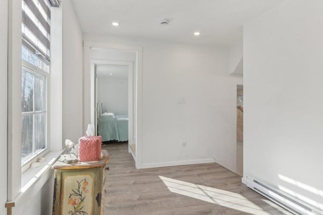 interior space featuring baseboard heating, a healthy amount of sunlight, and light hardwood / wood-style floors