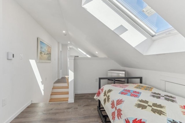 bedroom featuring wood-type flooring and vaulted ceiling with skylight