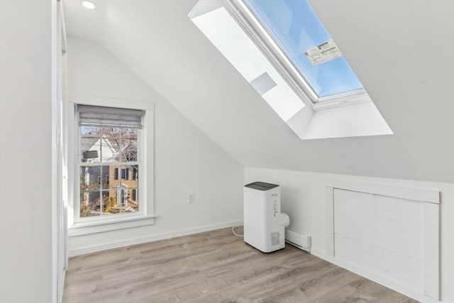 bonus room featuring vaulted ceiling with skylight and light hardwood / wood-style floors