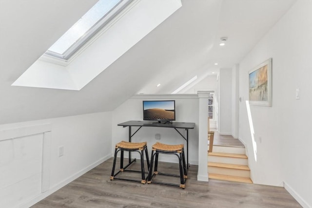 home office with light hardwood / wood-style flooring and lofted ceiling with skylight