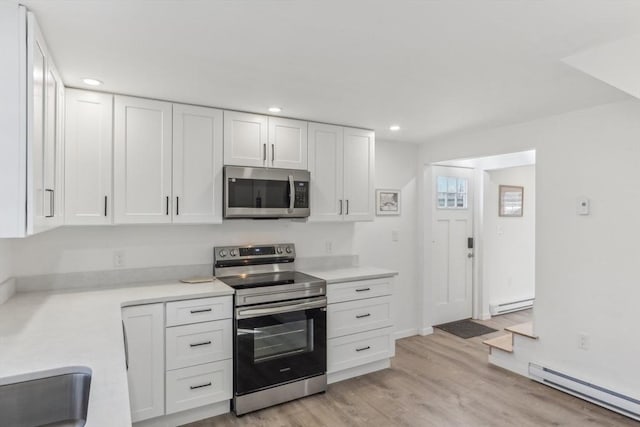 kitchen with white cabinetry, a baseboard radiator, and appliances with stainless steel finishes