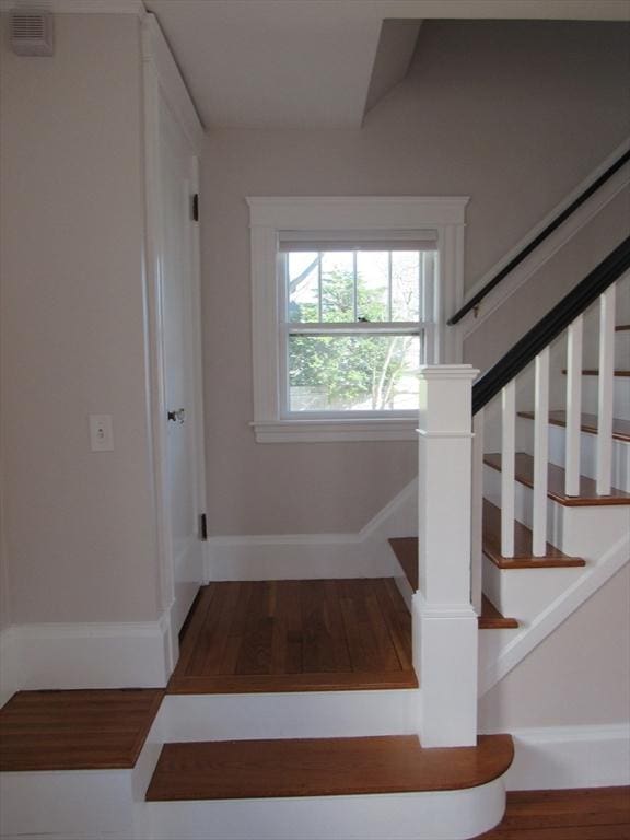 staircase featuring baseboards, wood finished floors, and visible vents