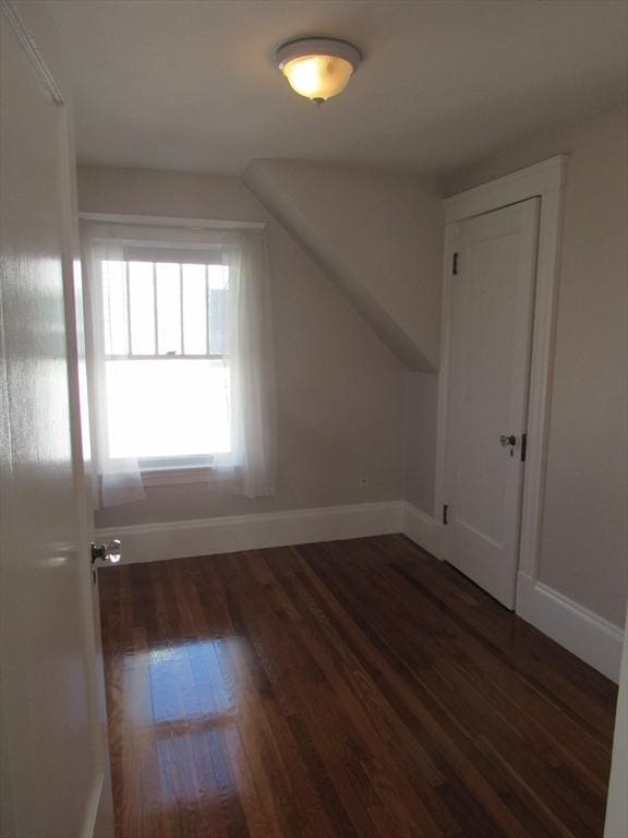 additional living space featuring baseboards and wood finished floors