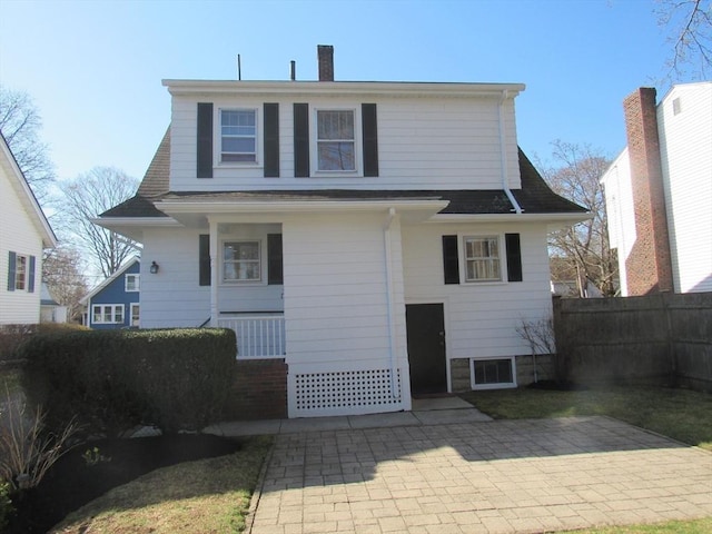 back of property featuring fence, a chimney, and a patio area