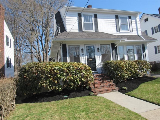 view of front of property featuring a shingled roof and a front lawn