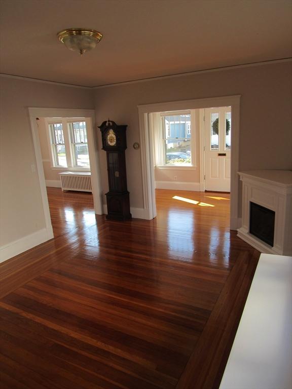 interior space featuring radiator heating unit, baseboards, a fireplace, and wood finished floors