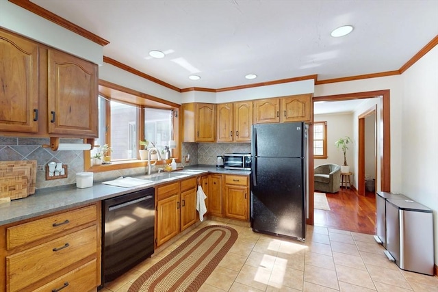 kitchen featuring crown molding, light tile patterned floors, brown cabinetry, a sink, and black appliances