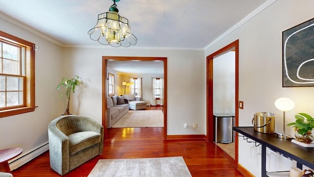 sitting room with ornamental molding, a healthy amount of sunlight, baseboard heating, and wood finished floors