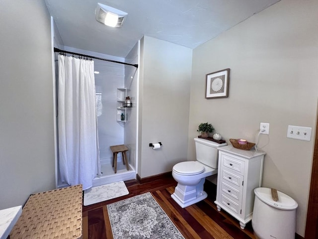 bathroom with baseboards, a shower stall, toilet, and wood finished floors