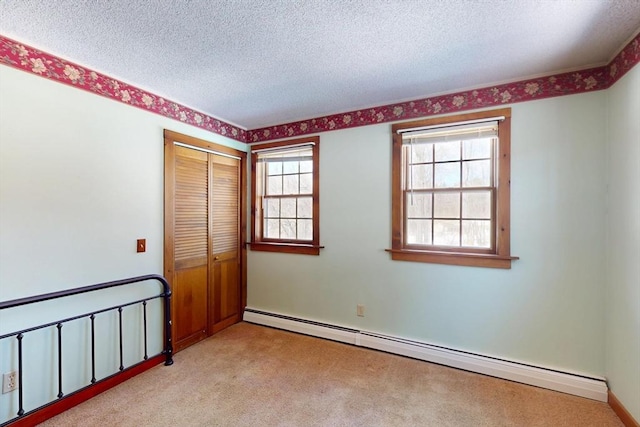 unfurnished bedroom featuring a closet, light colored carpet, a textured ceiling, and baseboard heating