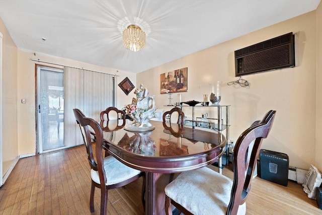 dining room featuring an inviting chandelier, a wall mounted AC, and light hardwood / wood-style floors