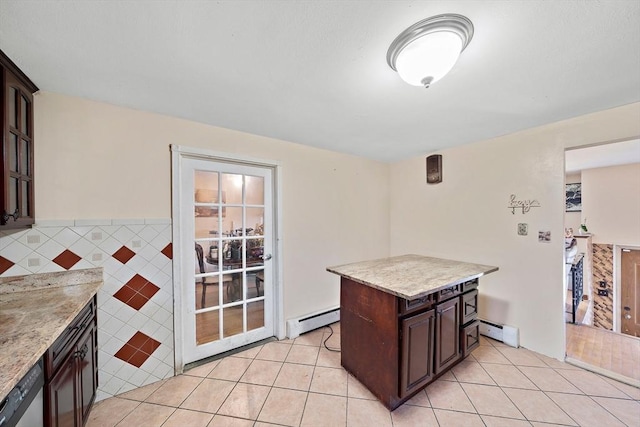 kitchen with dark brown cabinetry, a baseboard heating unit, light tile patterned floors, and stainless steel dishwasher