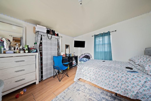 bedroom with vaulted ceiling and light hardwood / wood-style floors