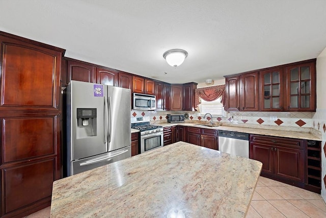 kitchen with tasteful backsplash, light tile patterned floors, stainless steel appliances, and light stone countertops