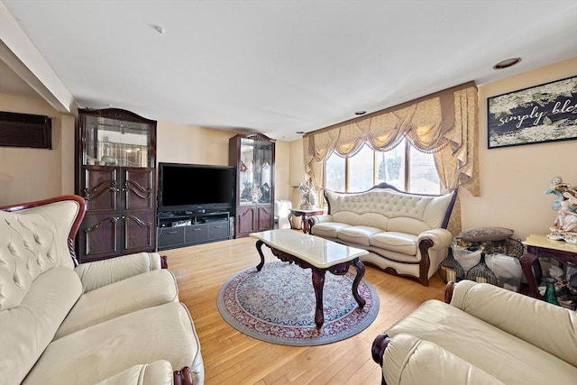 living room featuring light hardwood / wood-style flooring and an AC wall unit