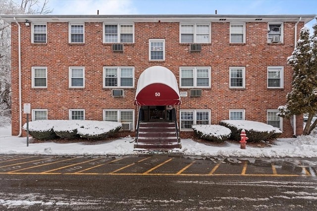 snow covered property with a wall unit AC