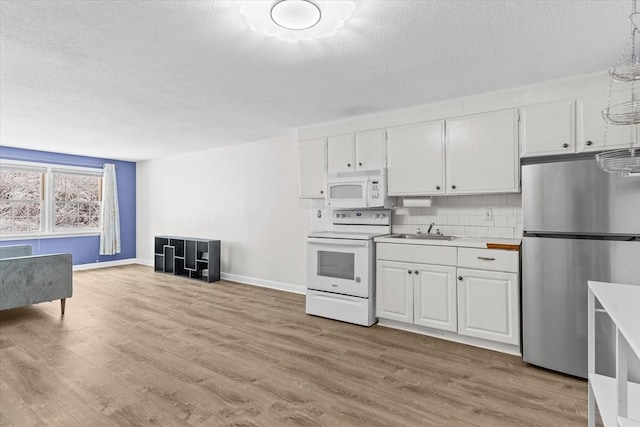 kitchen featuring white cabinetry, light wood-type flooring, white appliances, and decorative backsplash