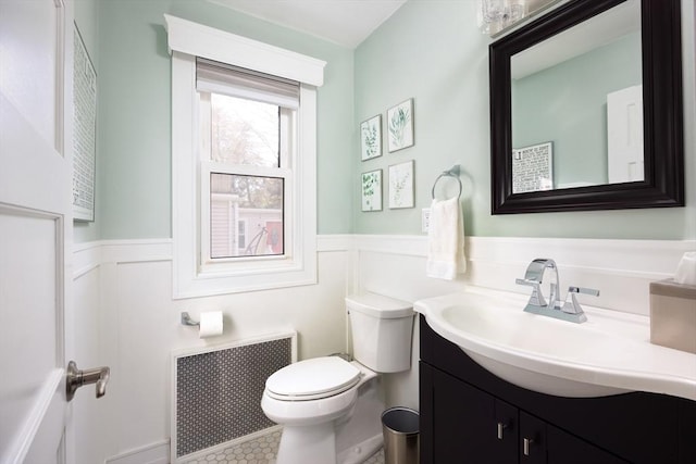 bathroom with radiator heating unit, wainscoting, vanity, and toilet